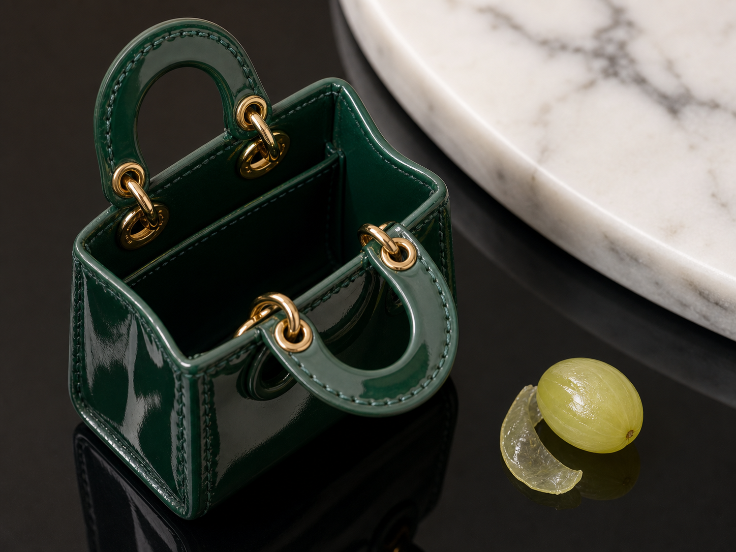 Open emerald micro tote with gold hardware and a peeled grape